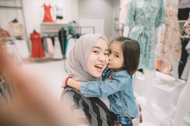 eine asiatische malay junge frau einkaufen in einem boutique-shop mit ihrer tochter selfie - boutique shopping retail mother stock-fotos und bilder