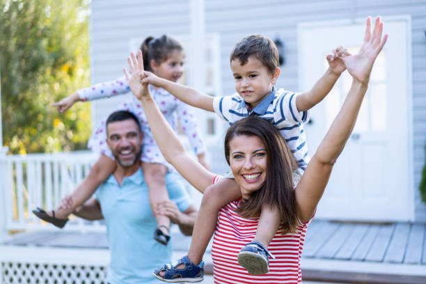 istock Family having fun in piggyback ride in front yard 1199890714