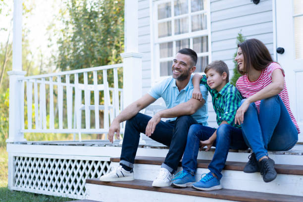 istock Family sitting on front steps of their house 1199890721