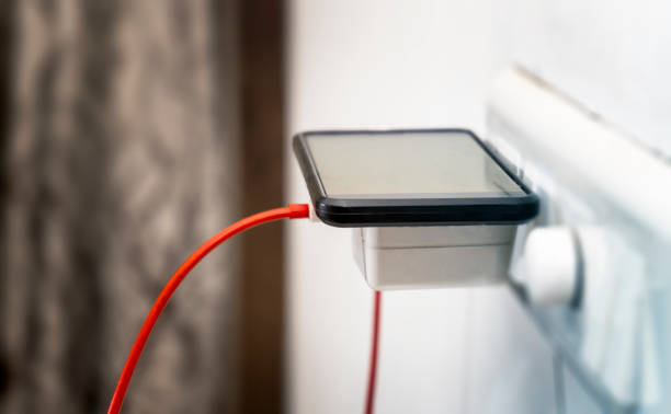 carregador do telefone móvel plugado na placa clara na casa - plug adapter charging mobile phone battery charger - fotografias e filmes do acervo
