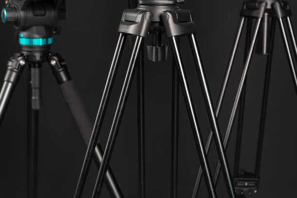 istock Three professional video photo camera tripods on black studio background 1199894118