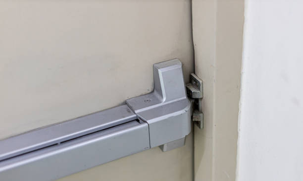 istock Emergency fire exit door. Closed up latch and rusty door handle of emergency exit. Push bar and rail for panic exit. Open one way door.  steel of handle for the white door fire exit 1199894365