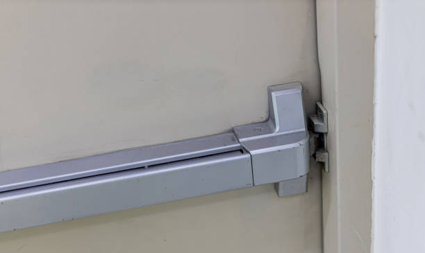istock Emergency fire exit door. Closed up latch and rusty door handle of emergency exit. Push bar and rail for panic exit. Open one way door.  steel of handle for the white door fire exit 1199894381