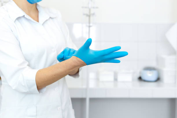 白衣を着た看護師は、明るい取り扱い室で医療処置の前にゴム手袋を着用します。 - lab coat nurse doctor female doctor ストックフォトと画像