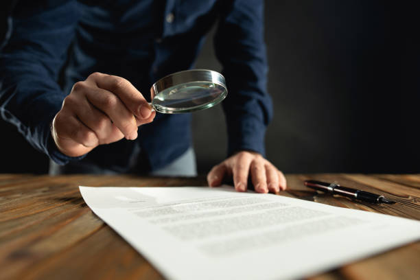 istock Businessman Reading Contract Using Magnifying Glass Before Signing 1199896200