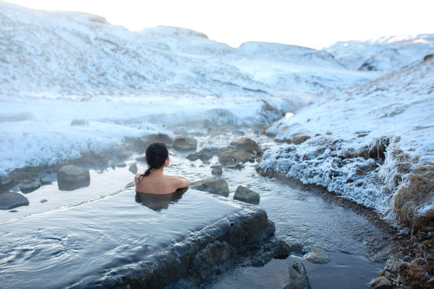 The girl bathes in a hot spring in the open air with a gorgeous view of the snowy mountains. Incredible iceland in winter The girl bathes in a hot spring in the open air with a gorgeous view of the snowy mountains. Incredible iceland in winter. lagoon stock pictures, royalty-free photos & images