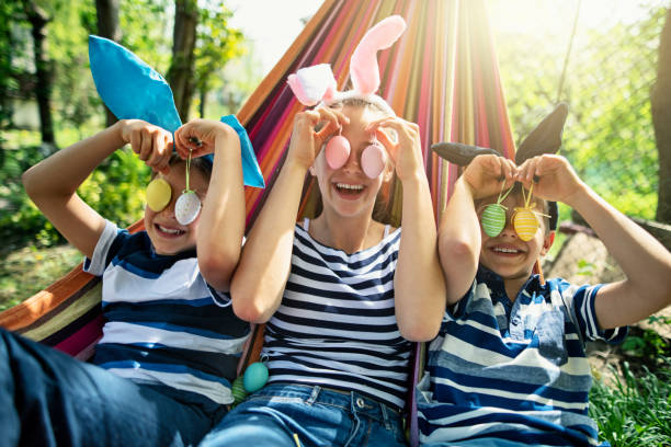 tres niños jugando con huevos de pascua encontrados en el patio trasero - easter easter bunny fun humor fotografías e imágenes de stock