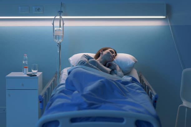 Woman lying in the hospital bed and sleeping with IV drip Young woman lying in a hospital bed at night and sleeping with IV drip night hospital bed stock pictures, royalty-free photos & images