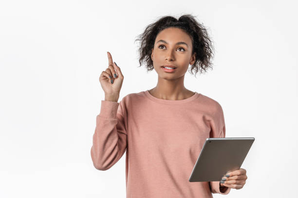 istock Excited woman pointing finger up and having an idea while holding tablet over white background 1199905280