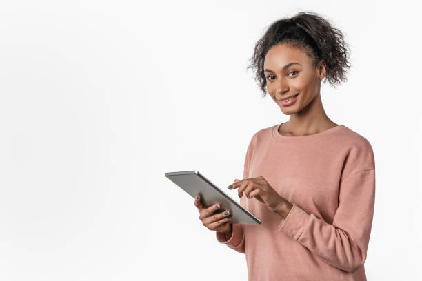 istock Young african woman standing and using tablet computer isolated over white background 1199905337