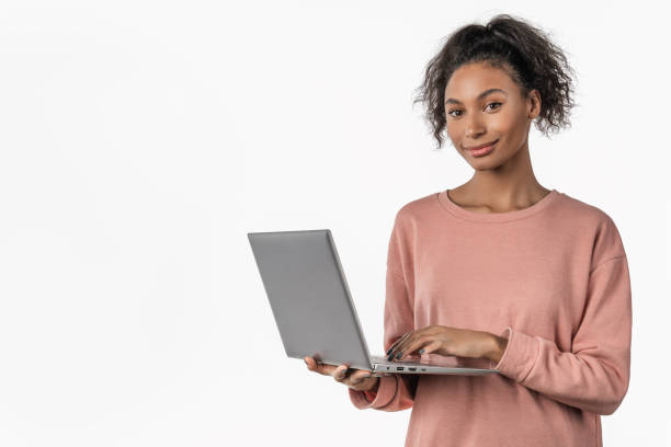 istock Happy young african girl using laptop computer isolated over white background 1199905425
