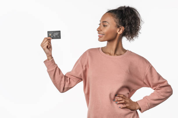 sonriendo joven feliz posando aislado sobre fondo blanco sosteniendo tarjeta de crédito - greeting card holding women credit card fotografías e imágenes de stock