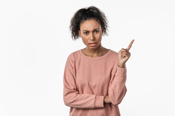 mulher americana africana que aponta com dedo acima e que está louca sobre o fundo branco isolado - women sadness isolated human face - fotografias e filmes do acervo