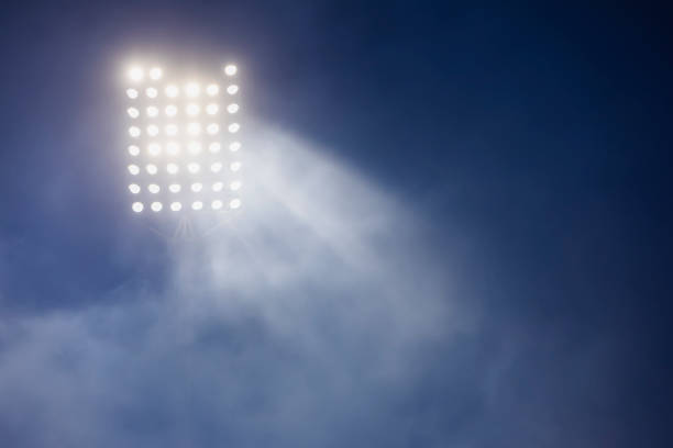 istock stadium lights and smoke against dark night sky background 1199907724