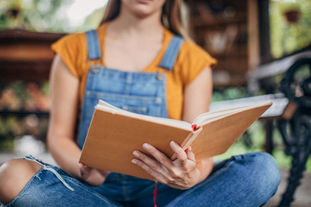 istock Young woman reading a book on a porch 1199910683