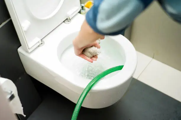 Female with sponge in a hand trying to stop a toilet overflow, blurred motion close-up