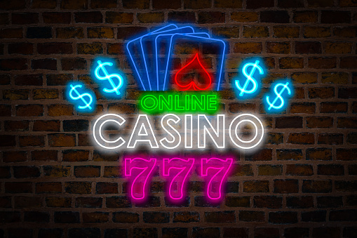 Light Neon sign with text Online Casino, Four playing cards and Three sevens for good luck against the backdrop of a ceramic wall. The concept of the advertising signboard site with gambling.
