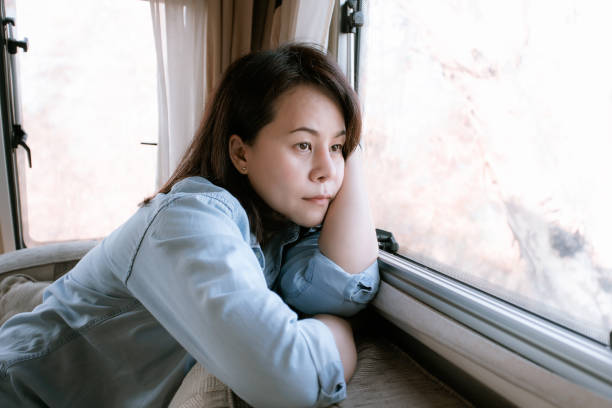 istock Lonely woman looking out the window in camper van. 1199912147
