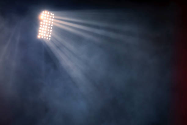 lumières de stade et fumée sur le fond sombre de ciel de nuit - illuminé par projecteur photos et images de collection