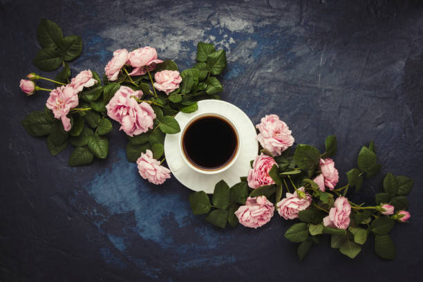 istock White cup with black coffee and pink roses on a dark blue backgr 1199917577