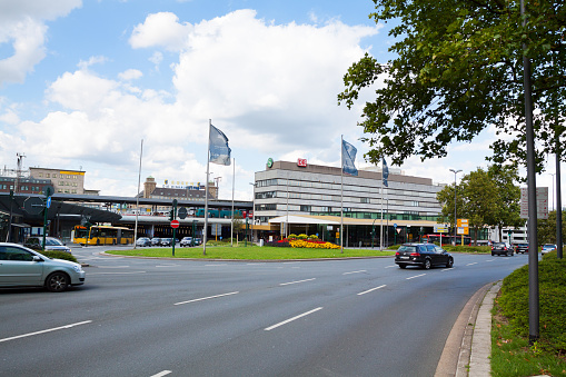 Main station Essen seen from street Kruppstrasse. Traffic is ruling in street. In street are some flags. Summertime capture.