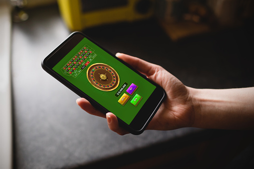 Online Roulette Game  against cropped hand of woman holding phone in kitchen