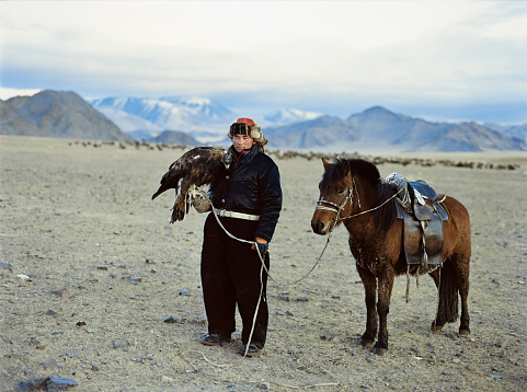 Portrait of eagle hunter on horse in desert in Mongolia