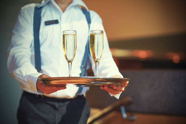 официант держит два бокала шампанского на подносе - butler champagne service waiter стоковые фото и изображения