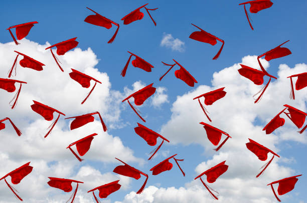red graduation caps in sky stock photo