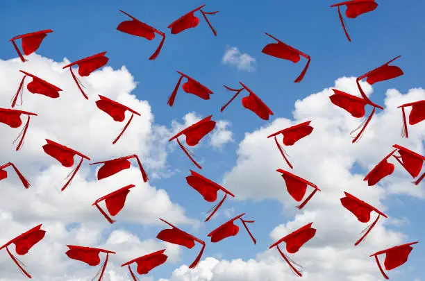 Photo of red graduation caps in sky