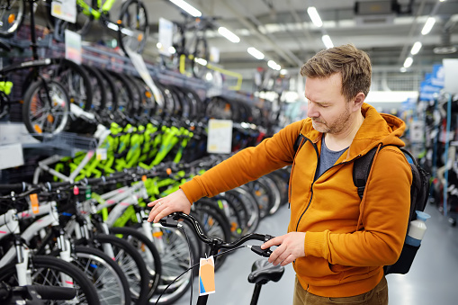 Middle age man choosing bicycle in sport store. Healthy active style of life.