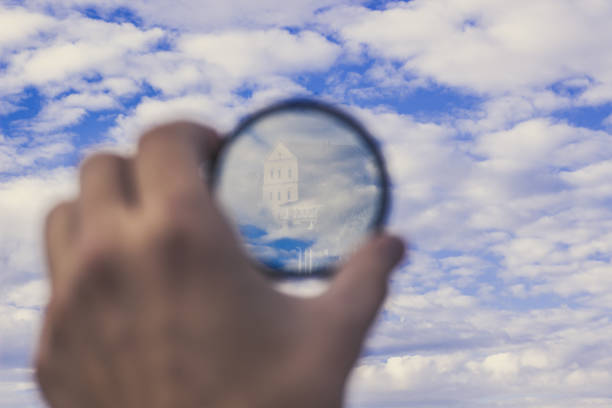 soft focus digital concept of human hand hold camera lens with reflection from building on blue sky with clouds background, copy space - magnifying glass lens holding europe imagens e fotografias de stock