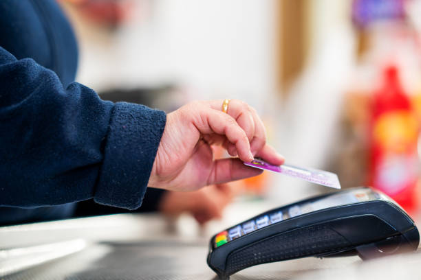 el primer plano del cajero está utilizando el terminal pos de la tarjeta de crédito sin contacto para obtener el pago. - edificio de transporte fotografías e imágenes de stock