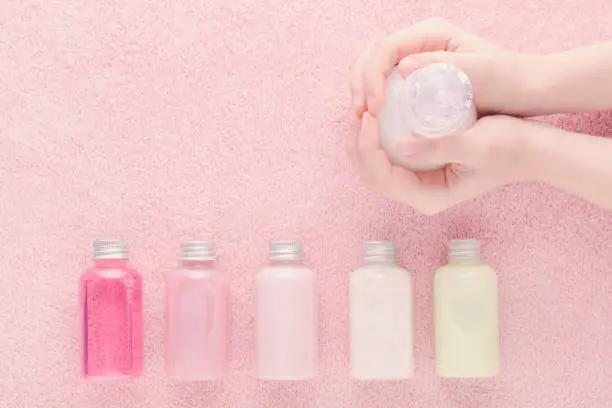 Photo of hands with a bottle and natural cosmetic bottles, shampoo, lotion, shower gel and other products, above