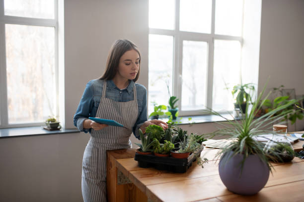 istock Smiling woman with a tablet checking her succulents 1199932606