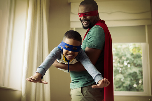 Hijo y padre fingiendo ser un superhéroe en casa photo