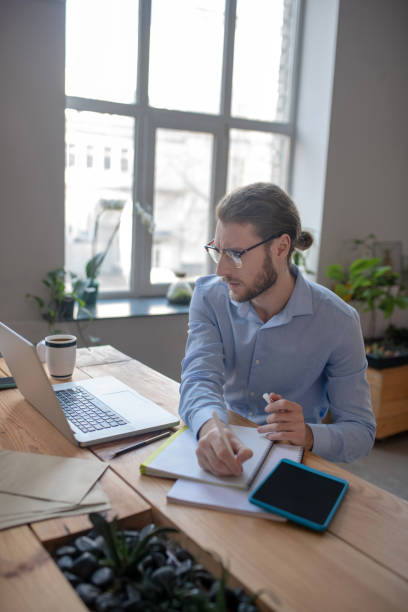 istock Successful man with pen in hand looking at laptop. 1199935255