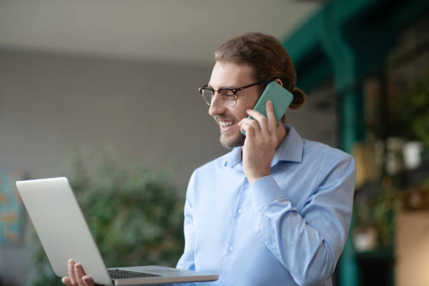 istock Successful young man with a laptop talking on a smartphone. 1199935328