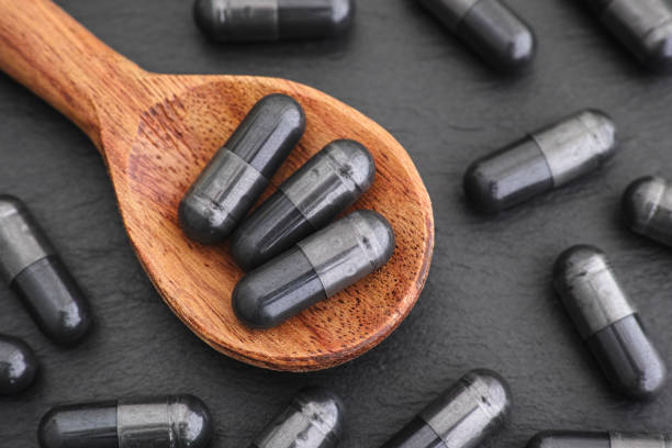 istock Activated vegetable charcoal capsules in a wooden spoon 1199935498