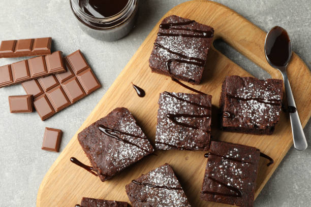 istock Board with chocolate cake slices and chocolate on grey background, top view 1199937992