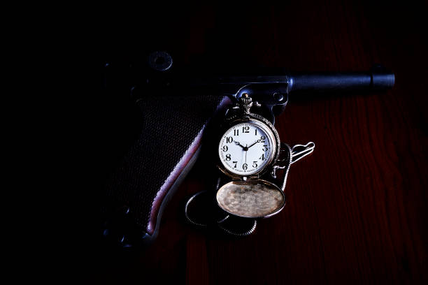 istock Pocket watch with gun and dark background 1199938590
