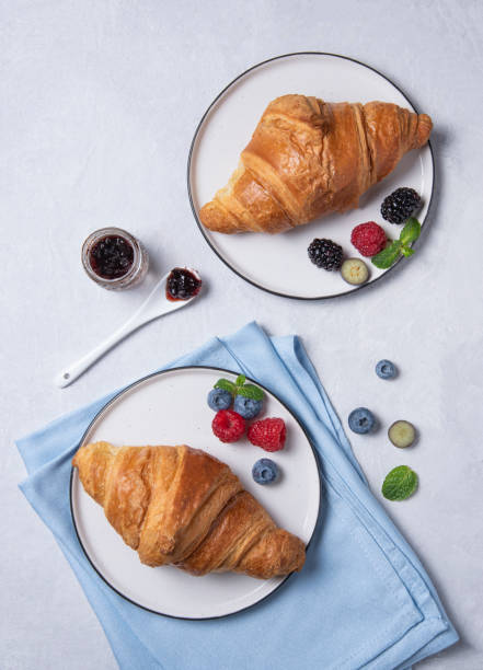 istock two fresh  croissant on a white plate  with jam, blueberries and raspberries on a gray background 1199942780