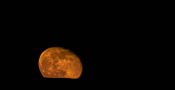 istock A Large, Orange, Nearly Full Moon Rises Over a Mountain Ridge at Night 1199944891