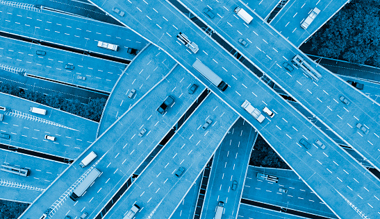 Cars, busses and trucks drive on multiple lane highways. Seen from above. Concept of mobility. 
The image is a 3D render.