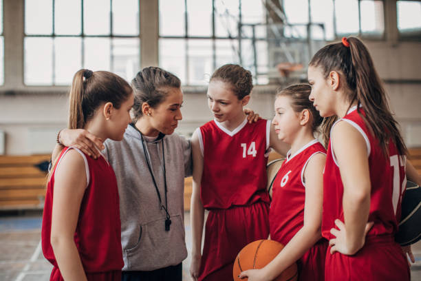 istock Coach standing with basketball team 1199947115