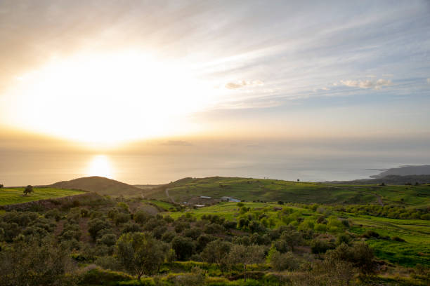 The sun is a bright flare across the sea and land