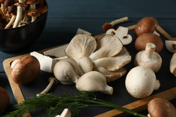 istock Different mushrooms, dill, bowl and board on wooden table, close up 1199949066