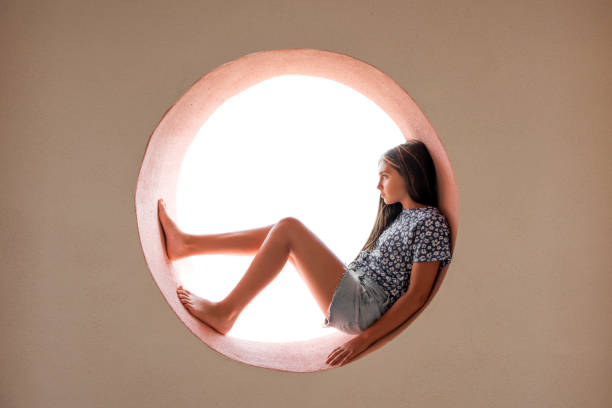 istock Young barefoot girl curled inside a round opening 1199950867