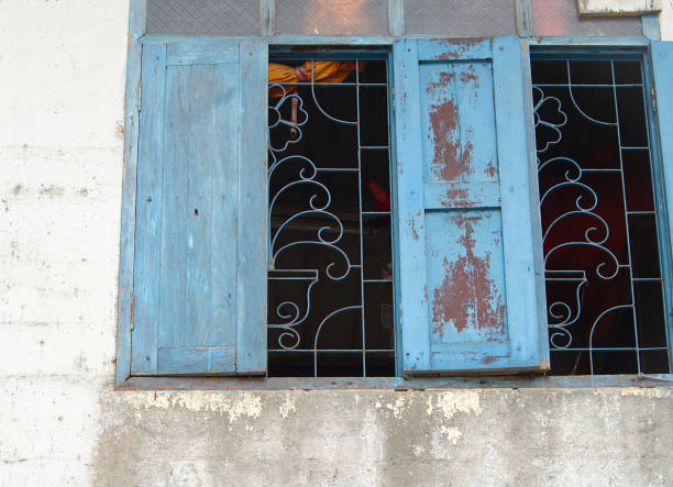 istock An old blue wooden window on an old peeling wall. 1199951354