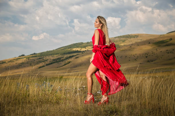istock Beautiful young blonde enjoys walking through grass in summer 1199952714